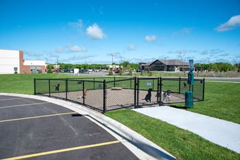A parking lot with a black fence and a green trash can.